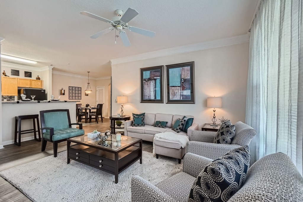 A living room with a white ceiling fan and a grey couch.
