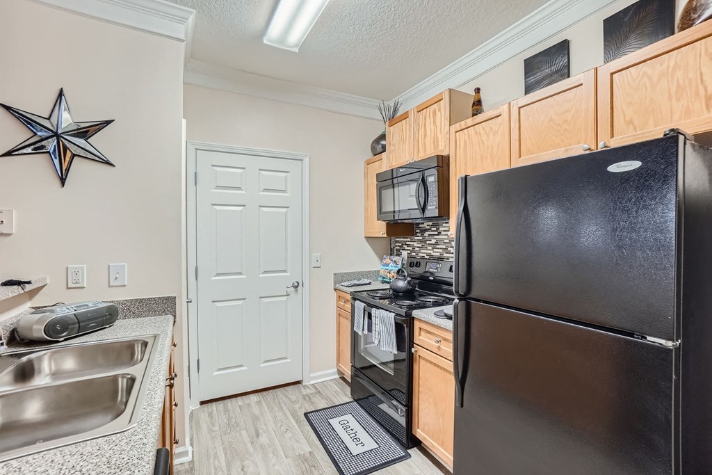 A black refrigerator is in a kitchen with a star decoration on the wall.