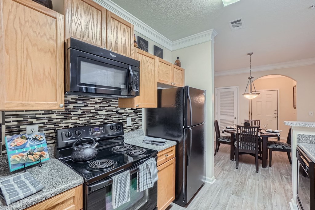 A kitchen with black appliances and wooden cabinets.