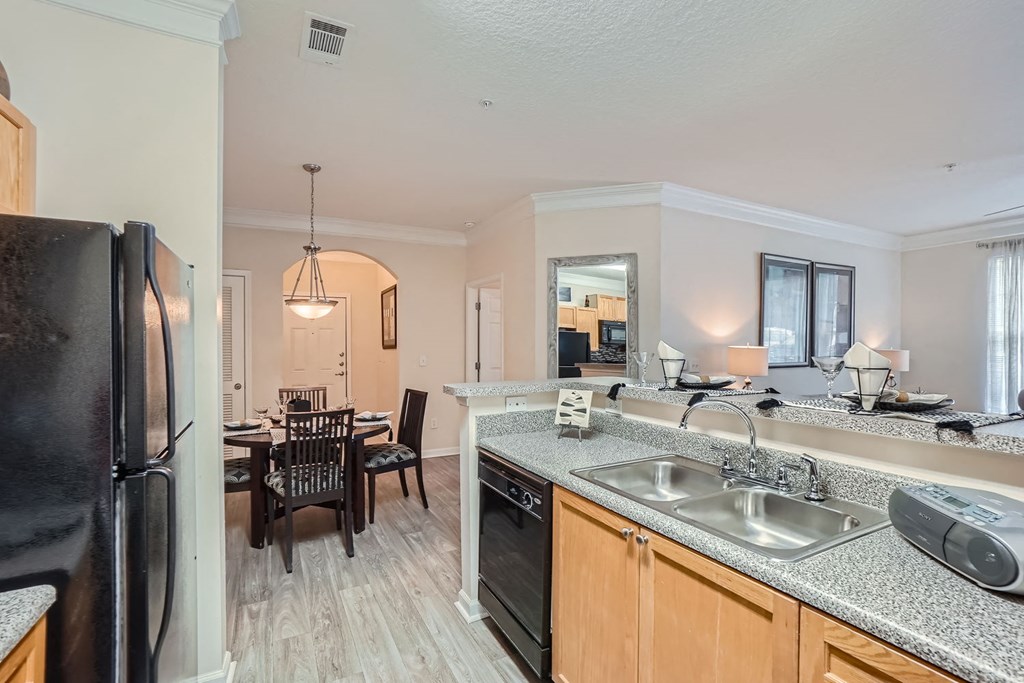 A kitchen with a black fridge, black oven, and a black dining table with chairs.