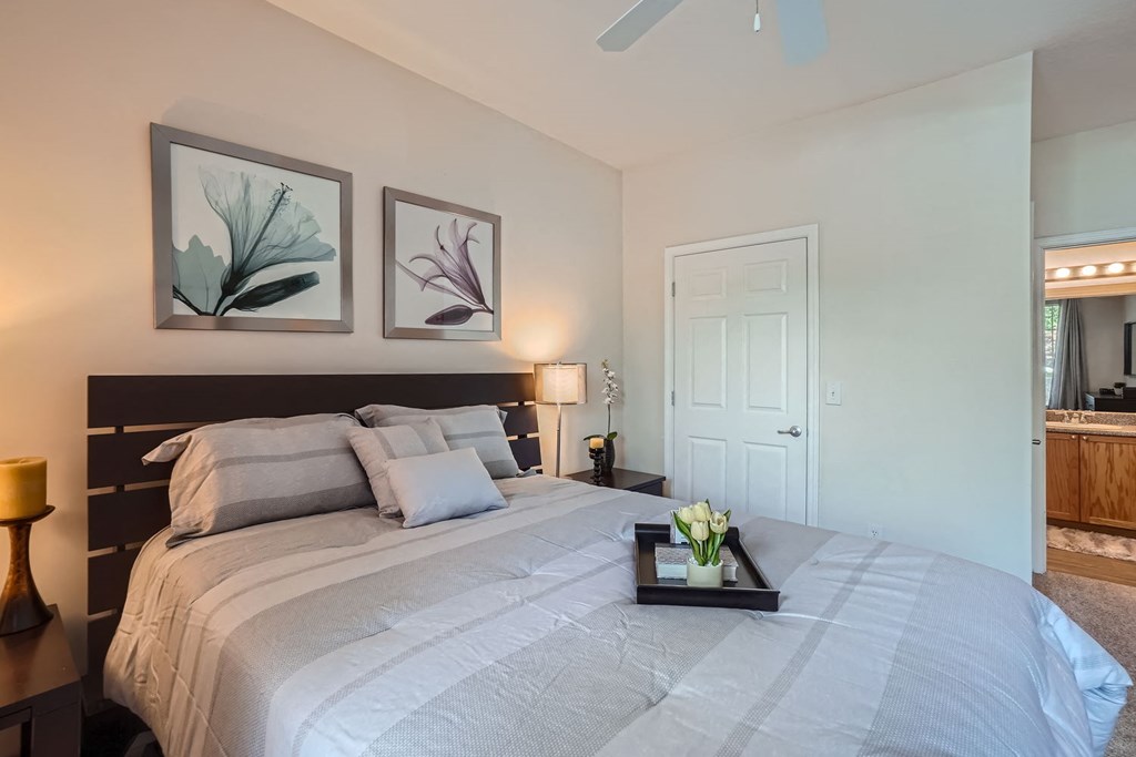 A bedroom with a large bed and two framed pictures on the wall.