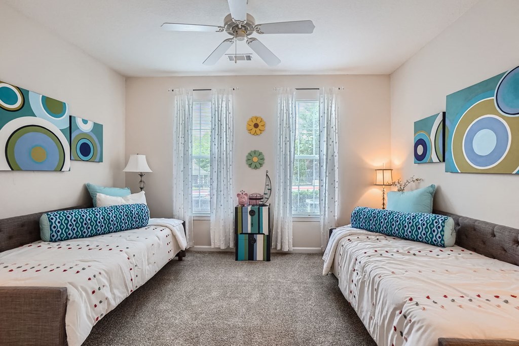 A bedroom with two beds and a ceiling fan.