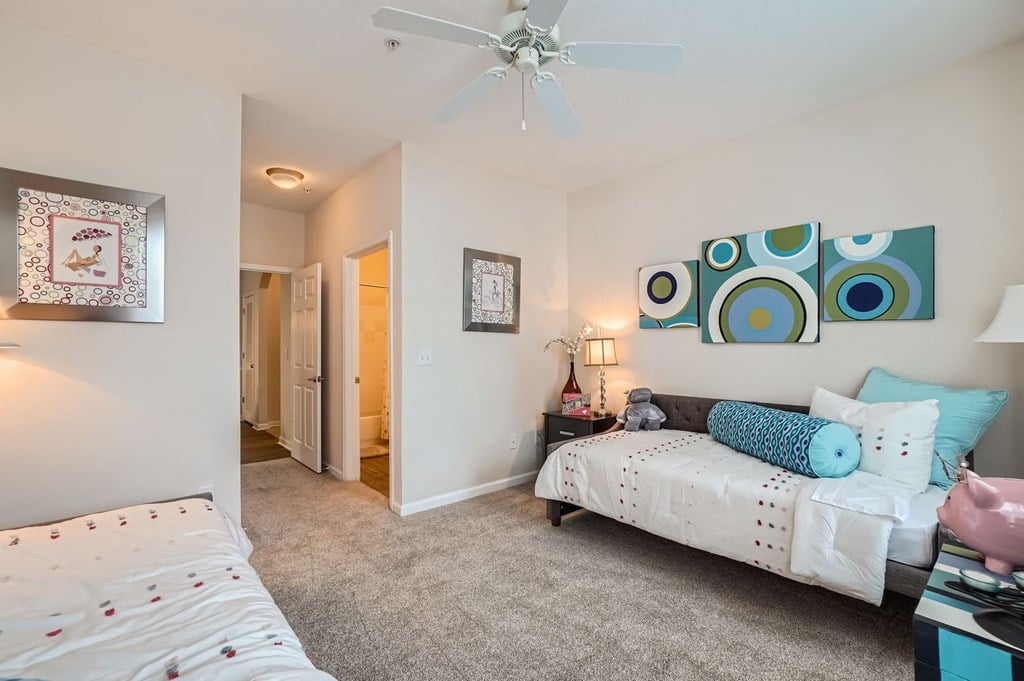 A bedroom with a bed, a couch, and a ceiling fan.