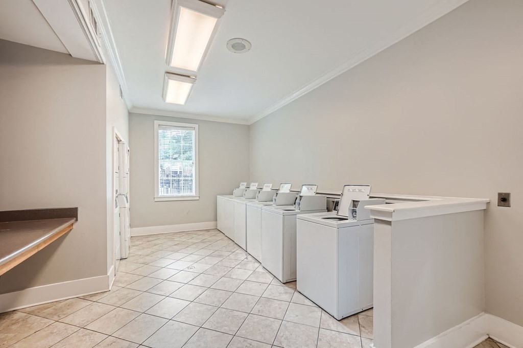 A row of white washing machines in a laundry room.