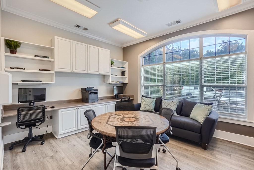 A well-lit room with a desk, chairs, and a couch.