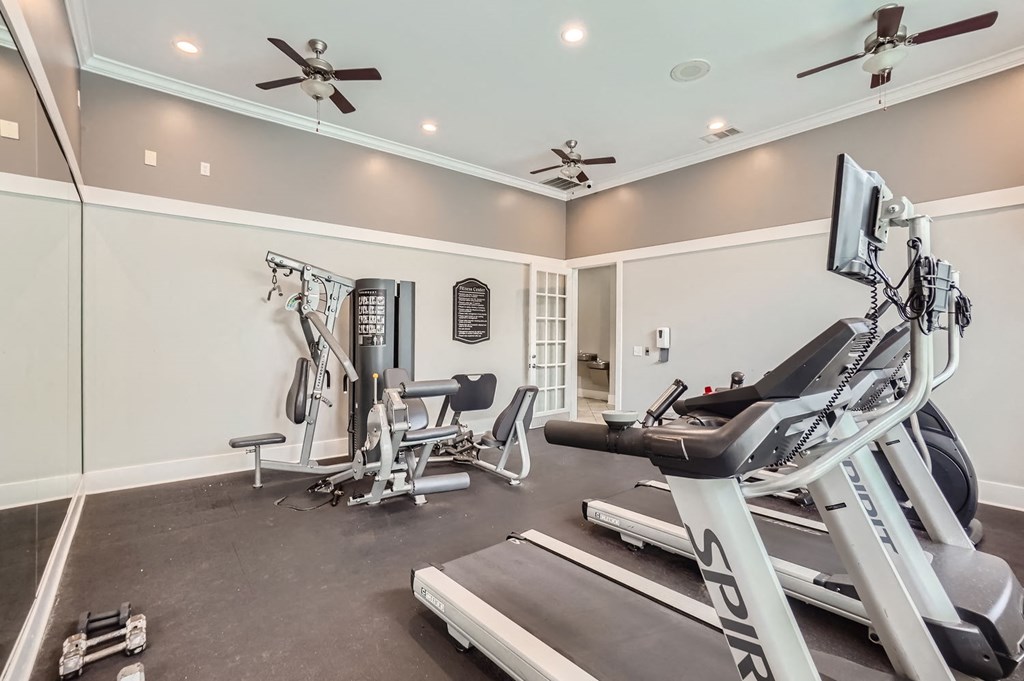 A spacious home gym with a treadmill, exercise bike, and other equipment.