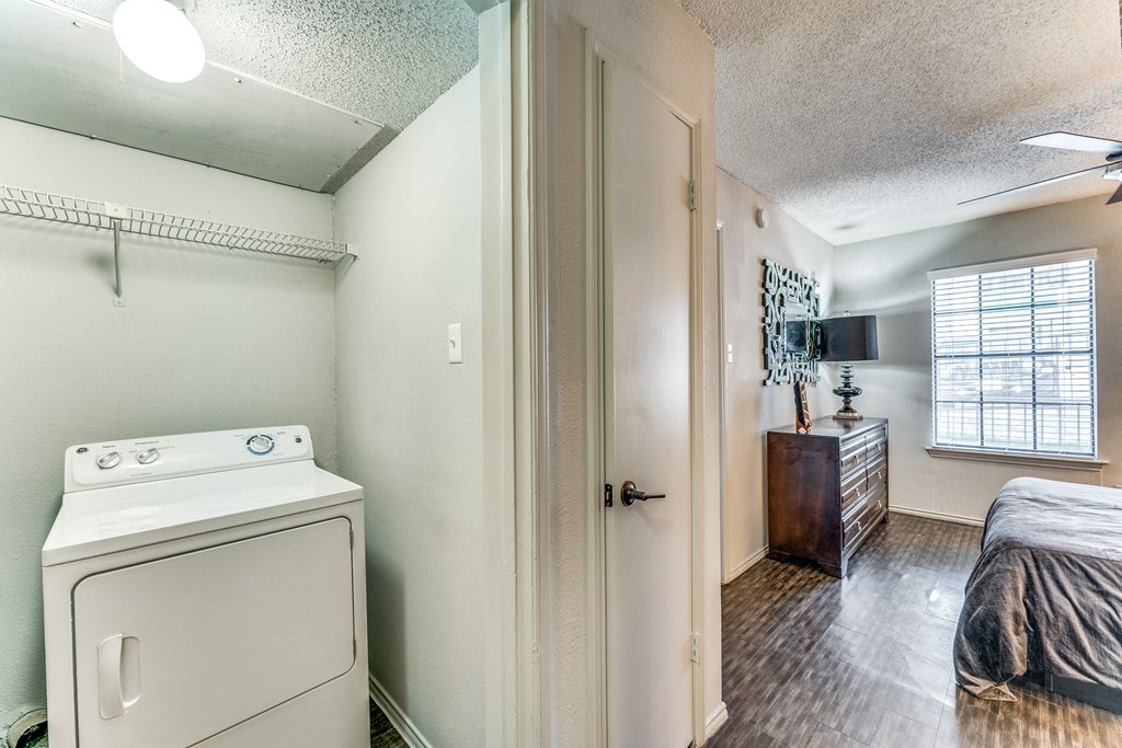 a room with a washer and dryer in it and a bedroom with a