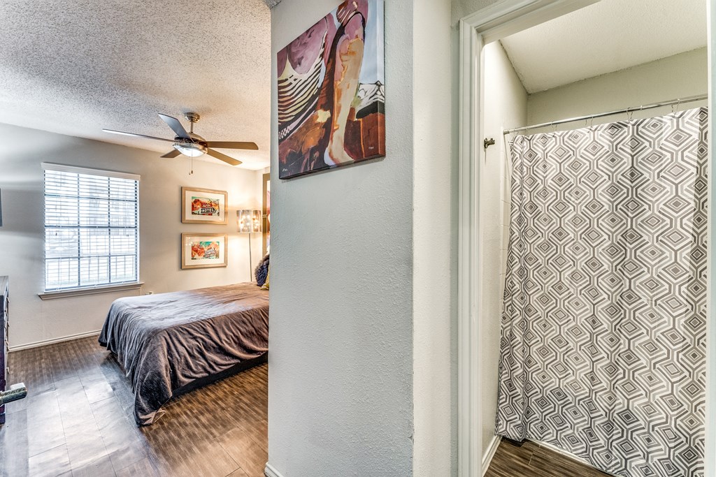 the master bedroom has a ceiling fan and a sliding door to the bathroom