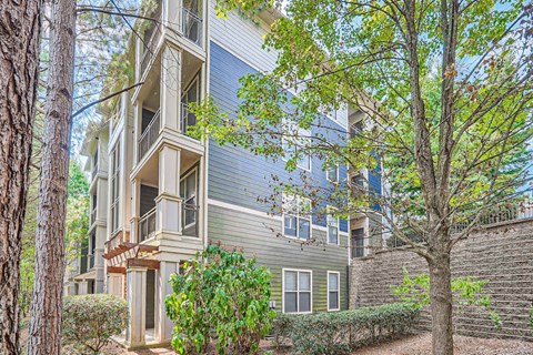 A tree in front of a grey building with a balcony.
