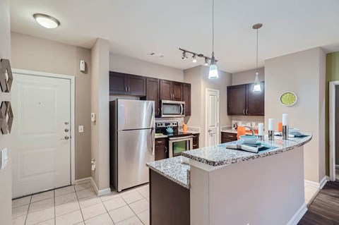 A kitchen with a granite counter top and stainless steel appliances.