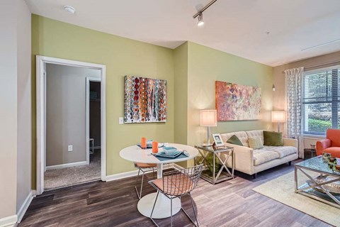 A living room with a white table and chairs, a couch, and a painting on the wall.