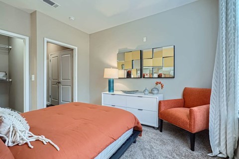 A bedroom with a bed, chair, and lamp.