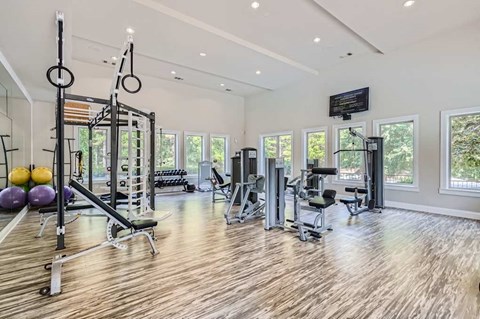 A spacious home gym with wooden floors and a variety of exercise equipment.