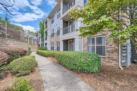 A residential building with a well-maintained lawn and a sidewalk.