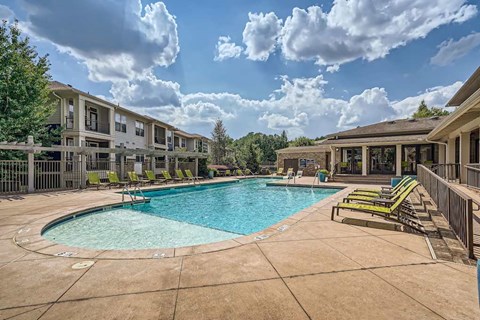 A swimming pool surrounded by lounge chairs and apartment buildings.