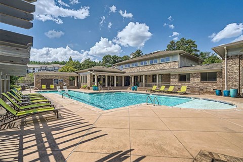 A swimming pool surrounded by lounge chairs and a building in the background.