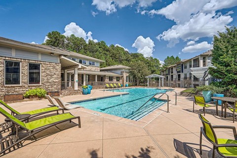A sunny day at a poolside with green lounge chairs.