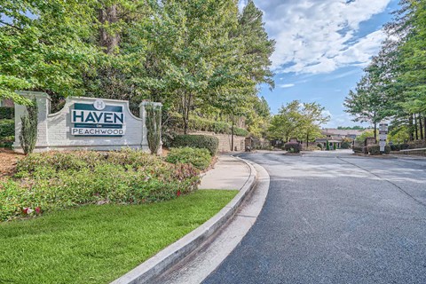 A sign that says Haven Peachwood is in front of a tree.