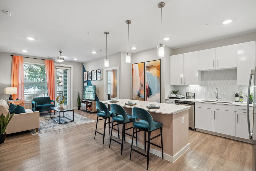 a living room with a kitchen and an island with blue chairs
