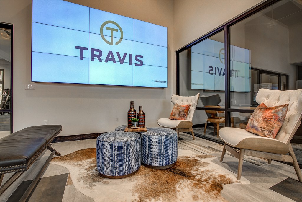 a lounge area with two chairs and a table with two bottles of wine on it
