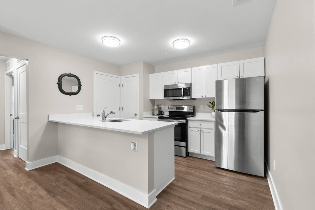 A kitchen with white cabinets and a stainless steel refrigerator.