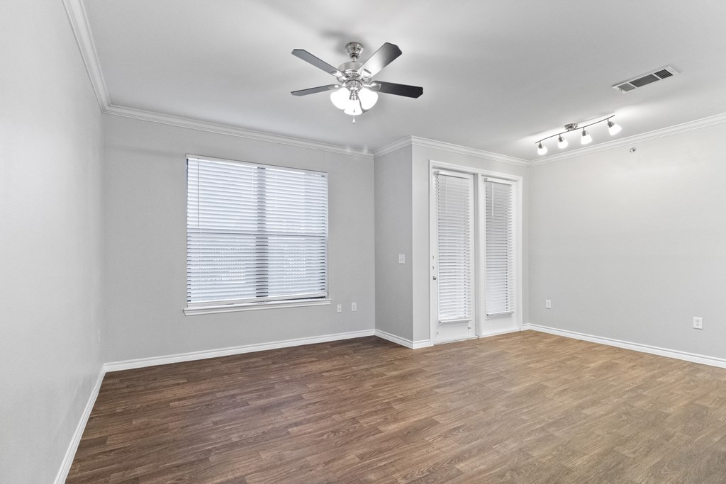 an empty living room with a ceiling fan and a window