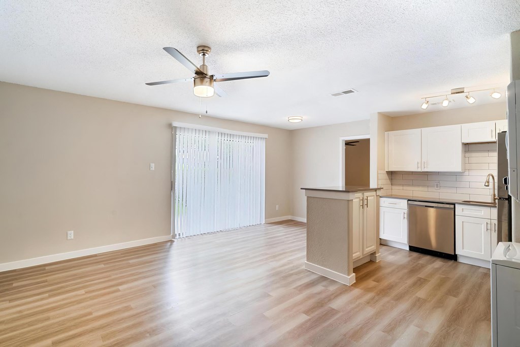 an empty living room and kitchen with a ceiling fan