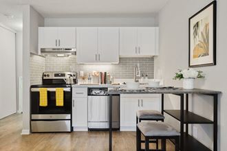 a kitchen with white cabinets and a black and white counter top with two stools