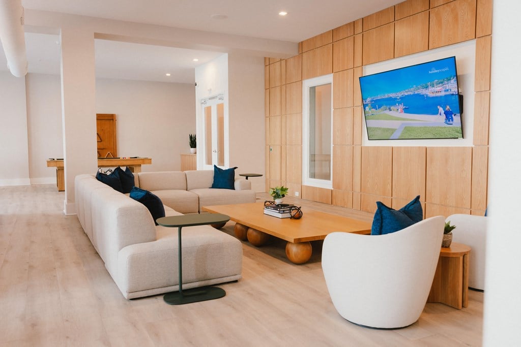 a living room with white couches and a coffee table and a television