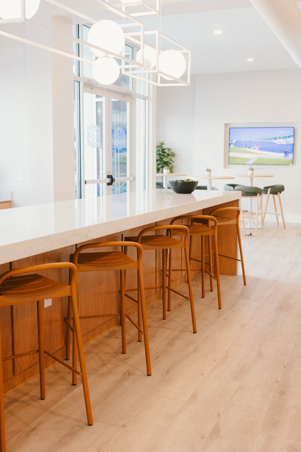 a kitchen with a long white counter top and wooden bar stools