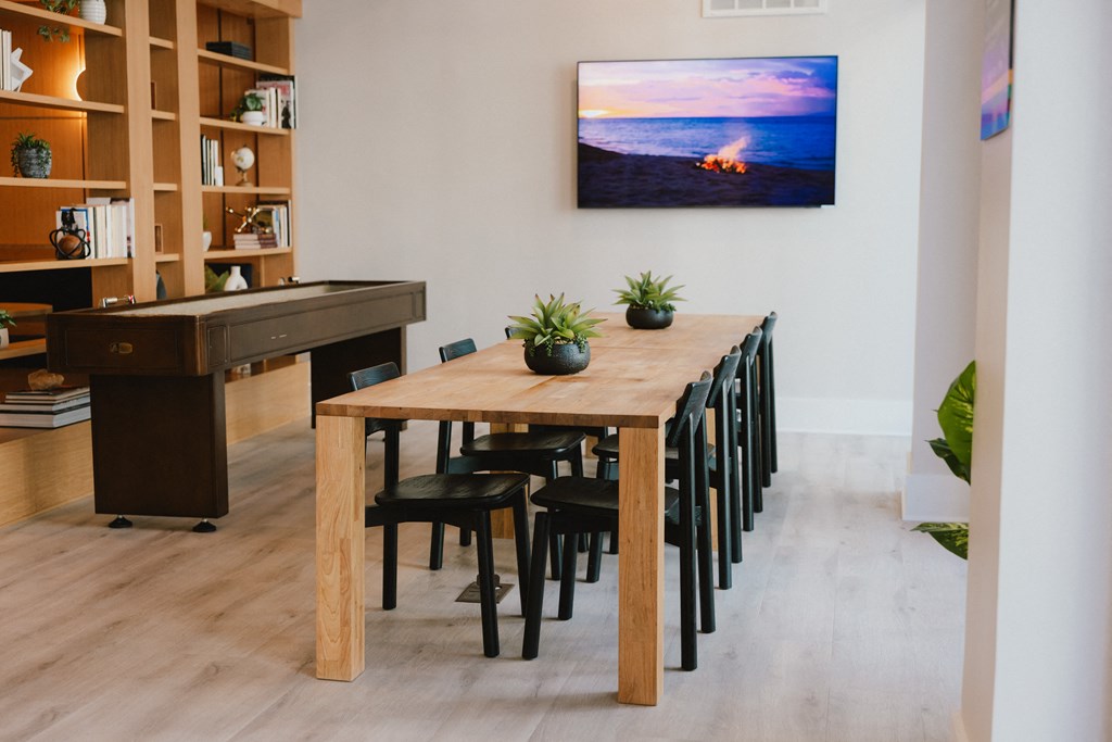 a long wooden dining table with black chairs and a piano