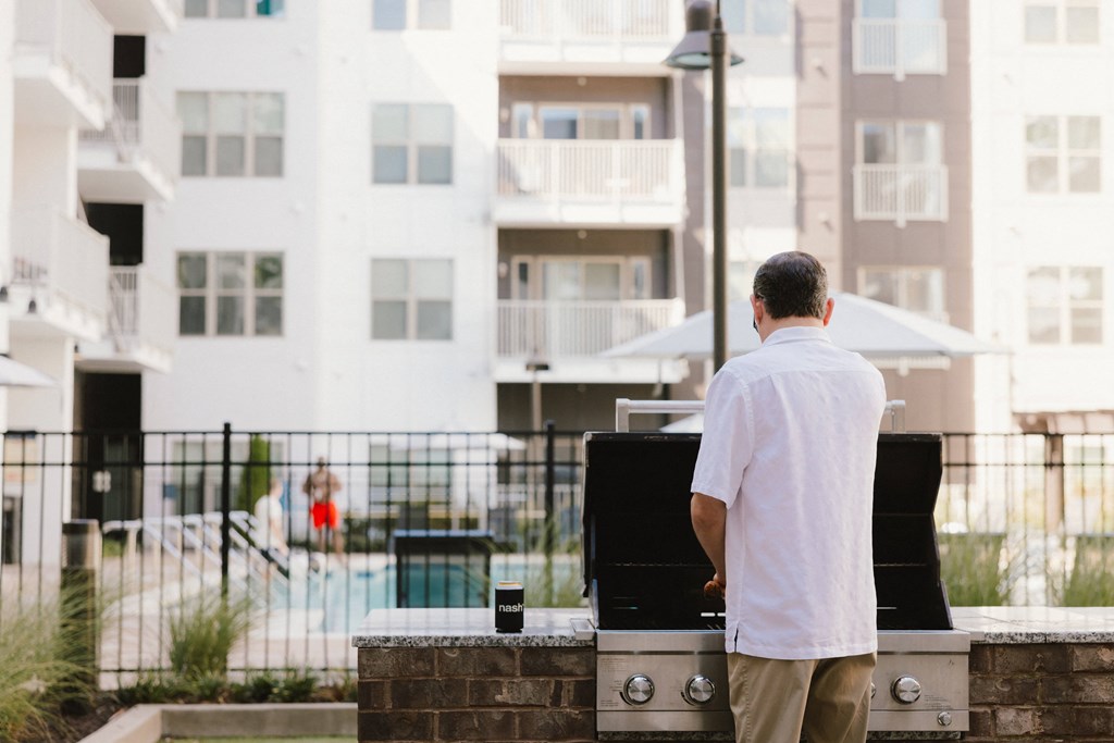 a man standing in front of an apartment building with a grill