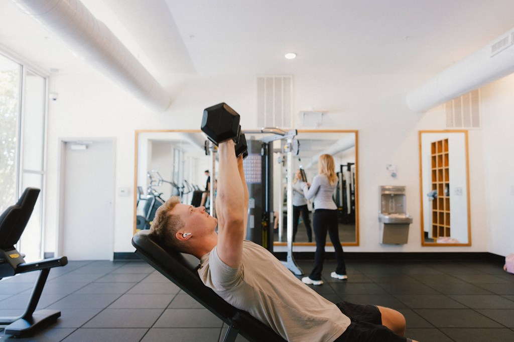 a man exercising in a gym with a dumbbell