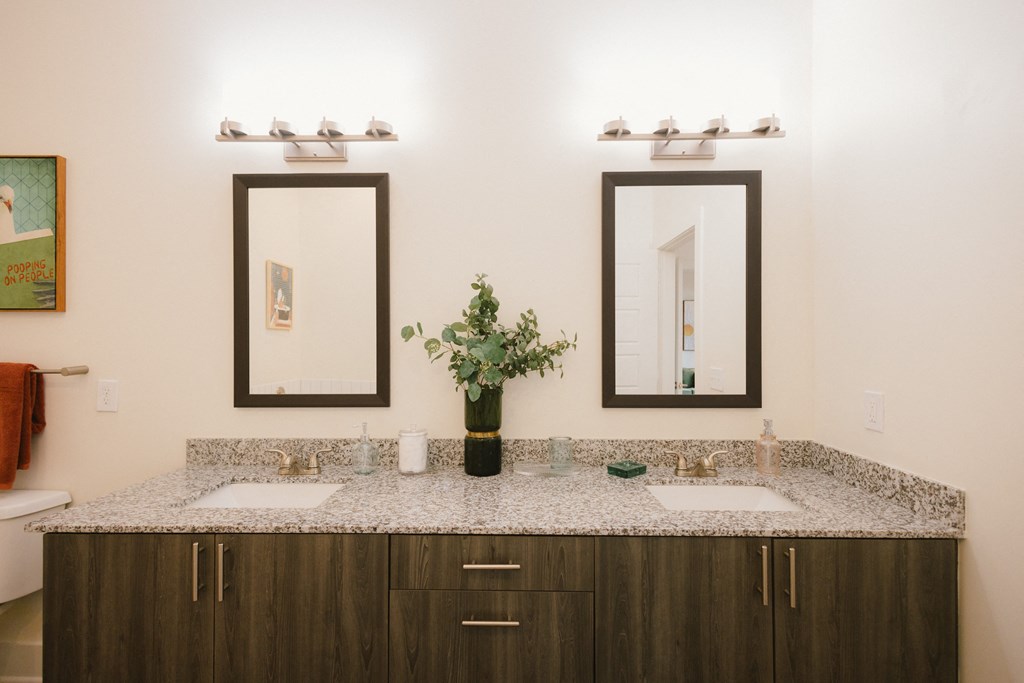 a bathroom with two mirrors and a counter with two sinks