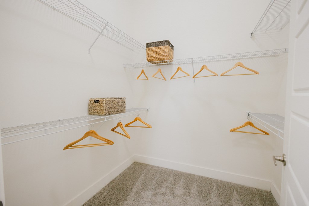 a closet with hooks and baskets hanging on the wall