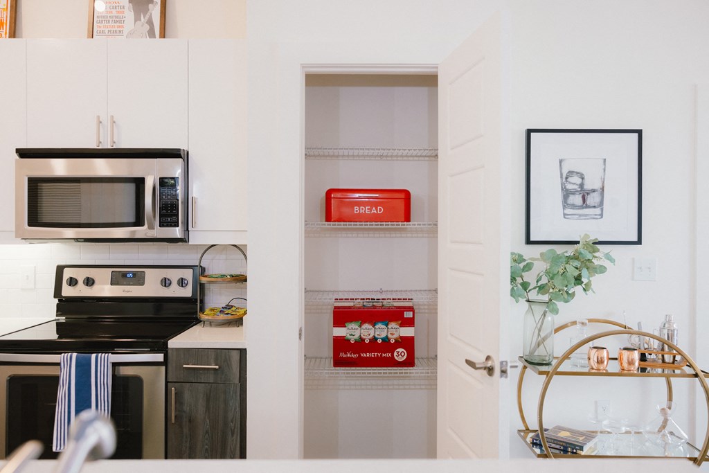 a kitchen with white cabinets and a microwave and a shelf with red boxes