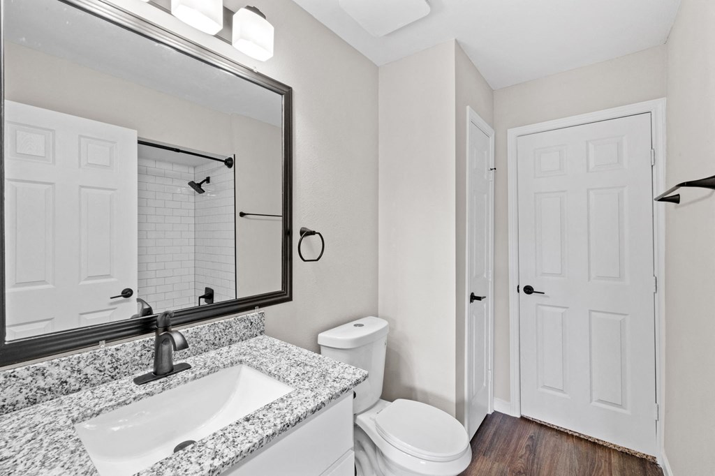 A bathroom with a granite countertop and white fixtures.