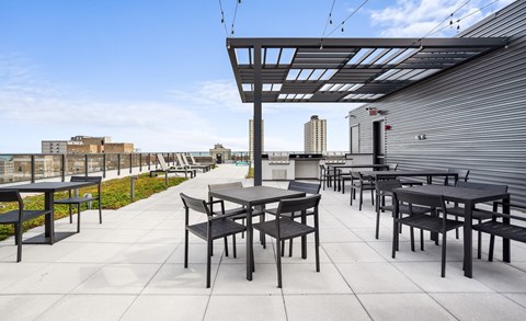 A patio with tables and chairs is covered by a roof with a metal frame.