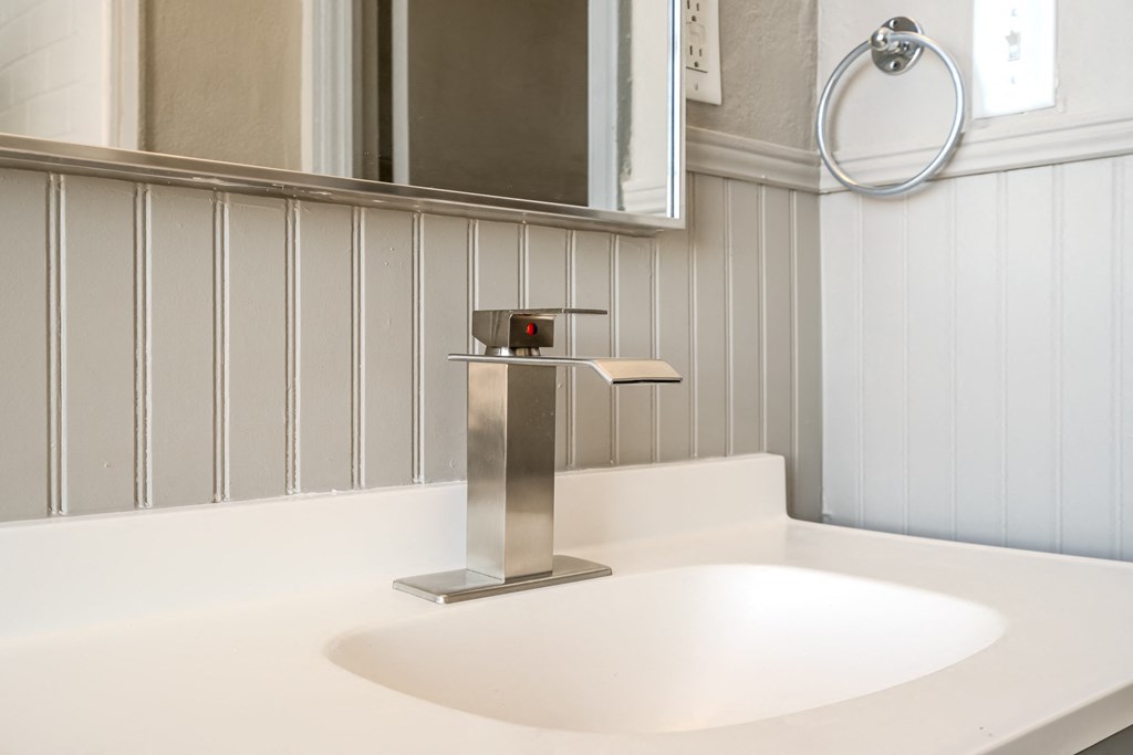 a white sink in a bathroom with a silver faucet