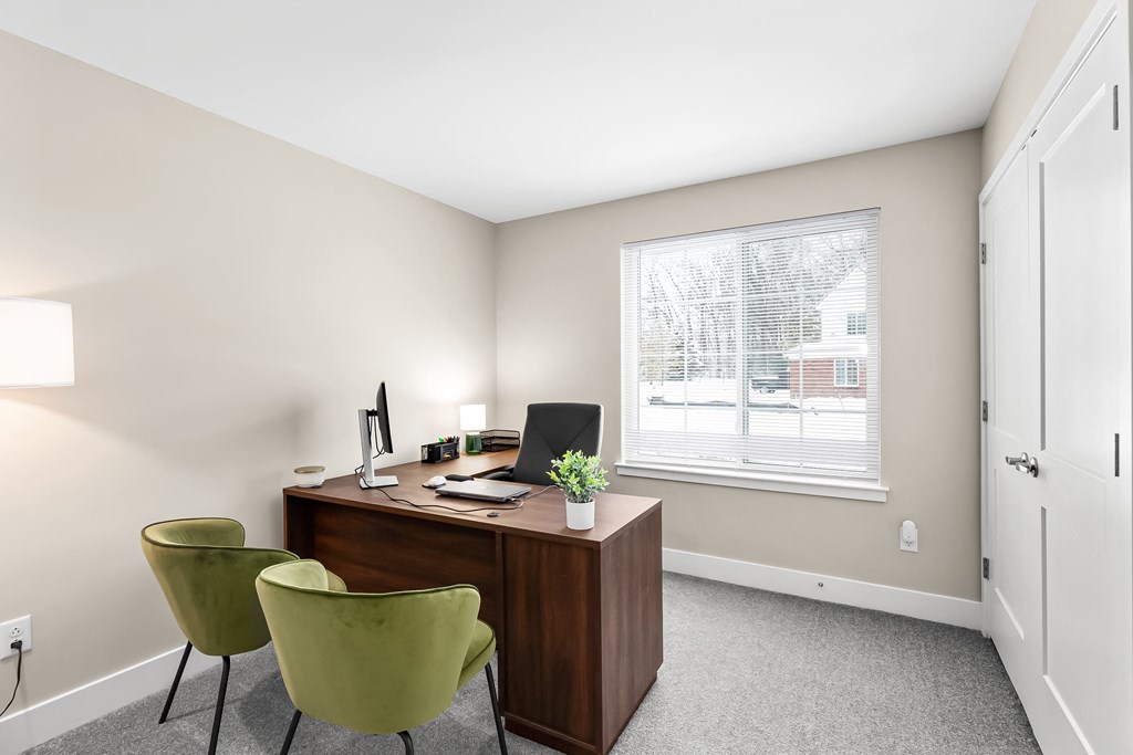 a home office with a wooden desk and green chairs
