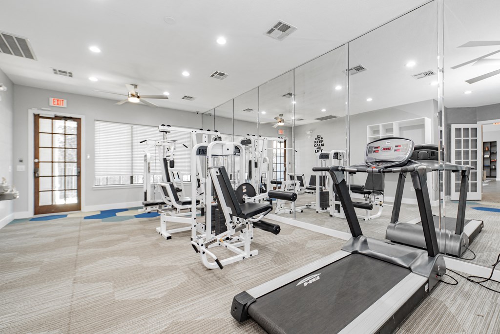 a gym with empty chairs and mirrored walls