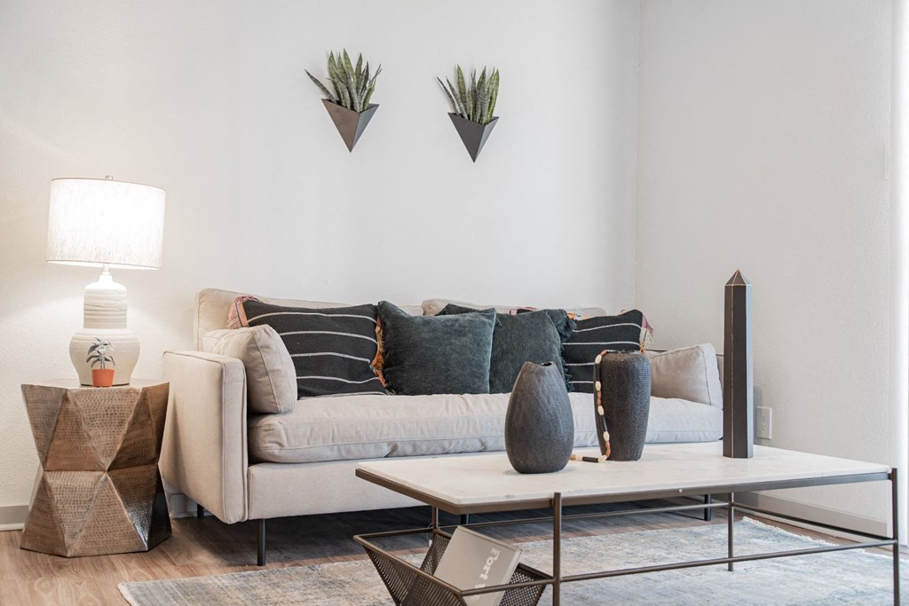 A living room with a grey couch, a white table, and a grey rug.