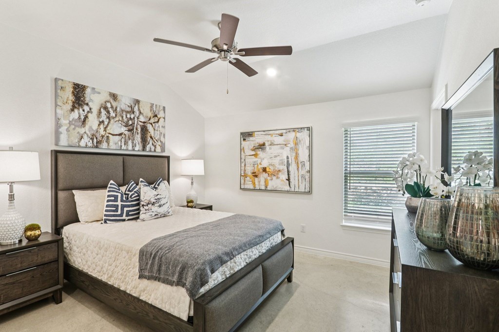 A bedroom with a large bed and a ceiling fan.