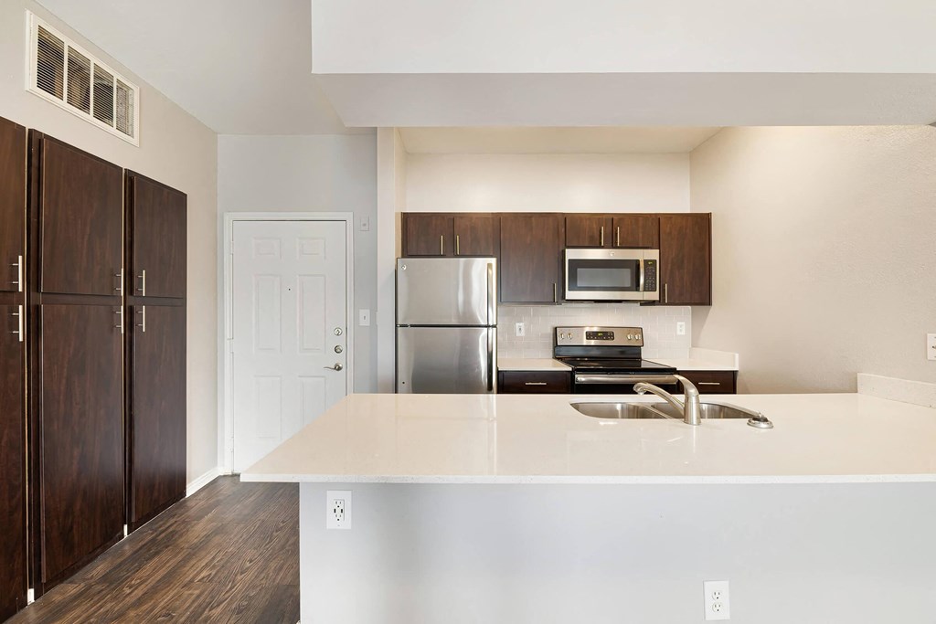 a kitchen with white countertops and a stainless steel refrigerator