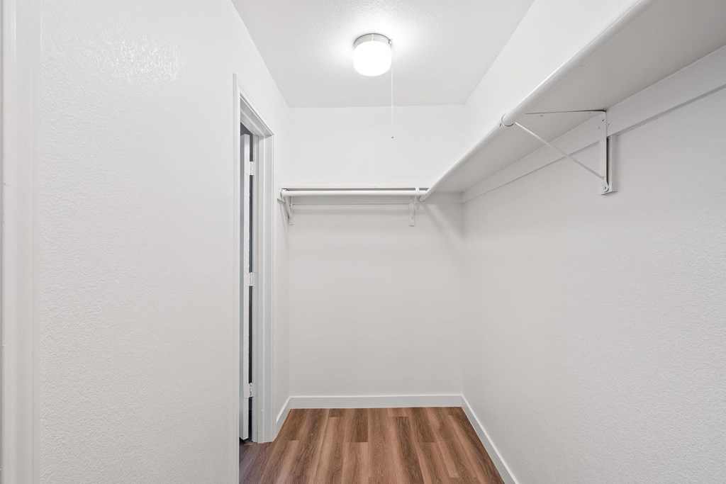 a bedroom with hardwood floors and white walls