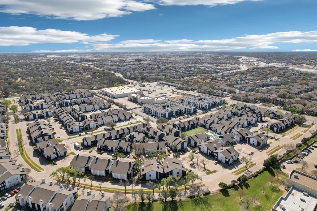 A large suburban housing development with rows of houses and a few cars parked in the driveways.