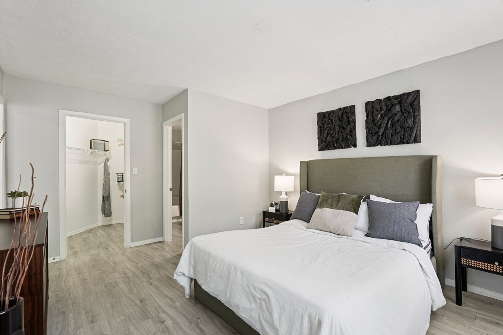 A bedroom with a large bed and two lamps.