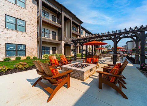 A patio with chairs and a table is surrounded by a building.
