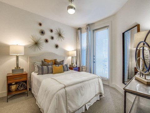 A bedroom with a large bed, a mirror, and a lamp.