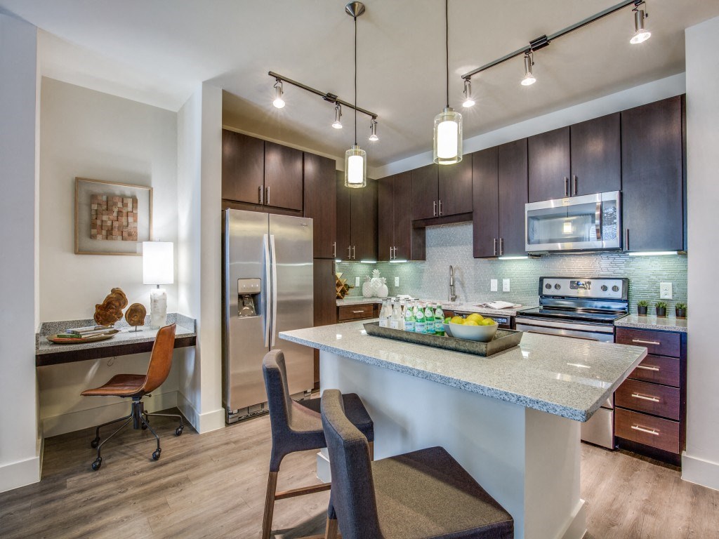a kitchen with a large island and a stainless steel refrigerator
